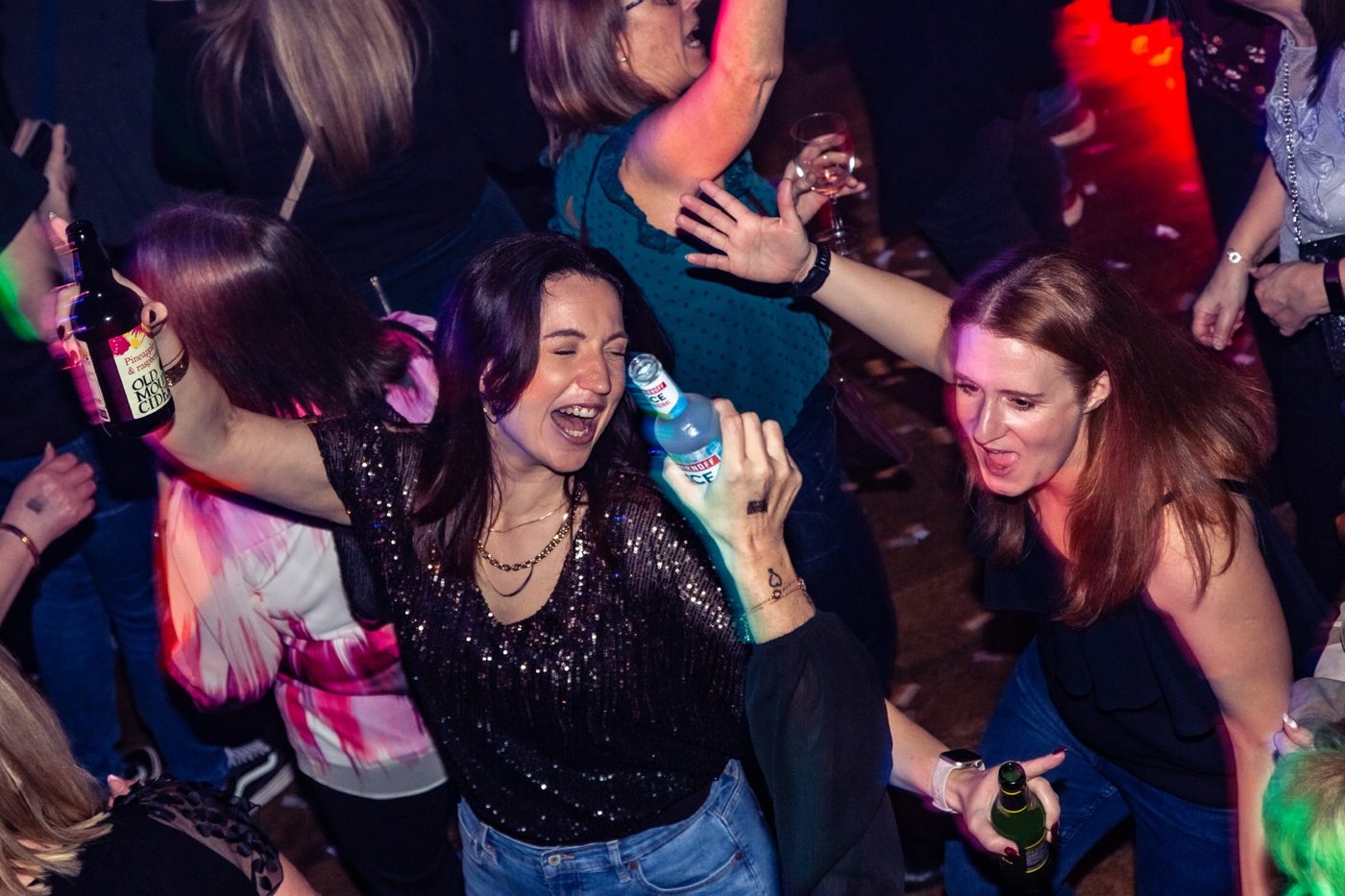 Two friends dancing mid-chorus, drinks in hand