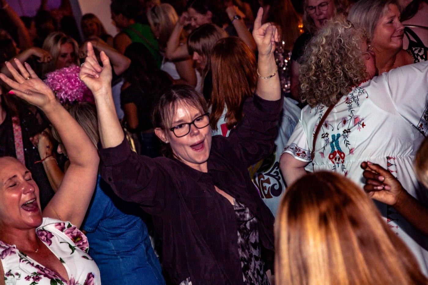 A guest smiling with arms raised in the crowd