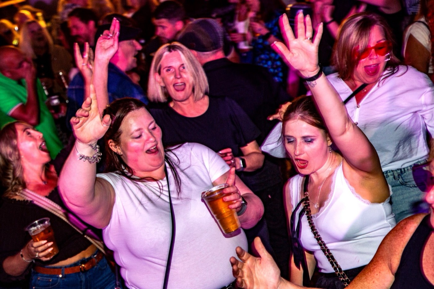 Three women with arms raised mid-chorus