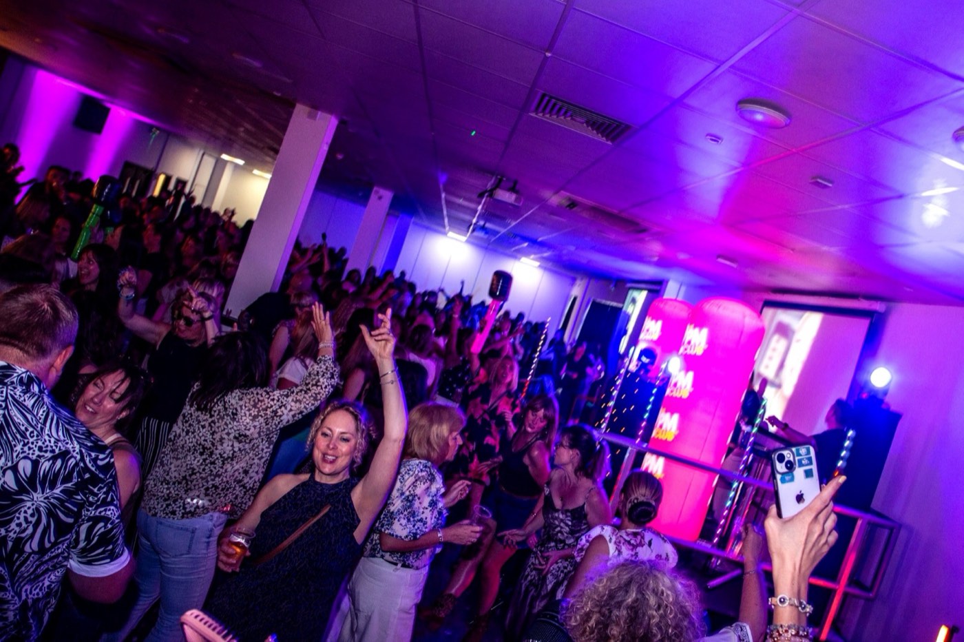 A packed room with arms raised towards the stage